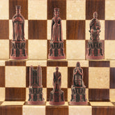 The burgundy coloured side of a hand made chess set inspired by the architecture and statuary in and around Medieval Cathedrals, a chess set of gracious proportions and great detail.